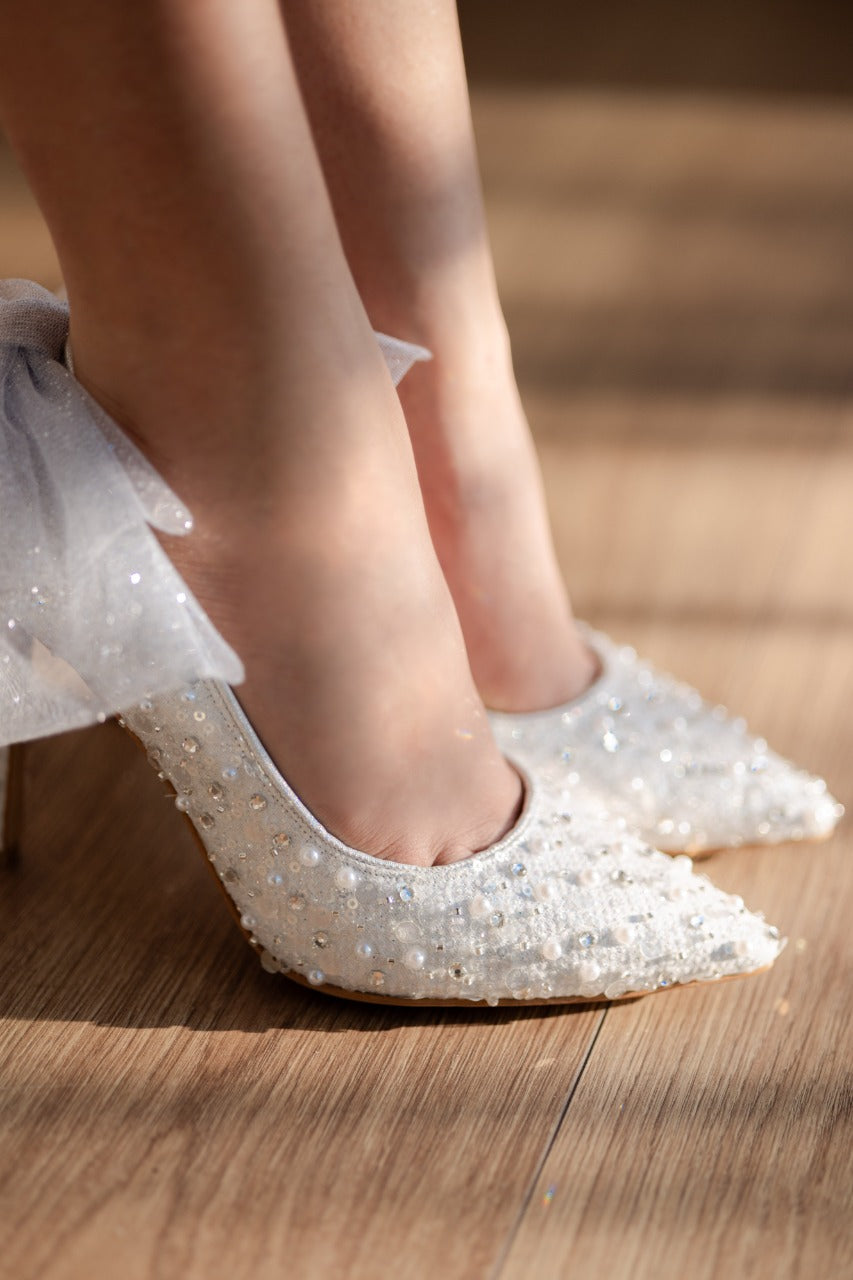 Stiletto de novia de tacón delgado con textil brilloso, lleva cristal austriaco, perla y aplicacion de moño en la parte de atras 